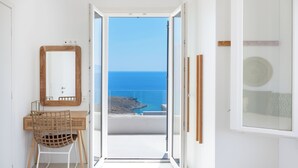 A room with a wooden desk, a chair, a mirror, and a view of the sea. - MZ Deep Blue (Kythnos)