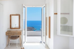 Ein Zimmer mit Holztisch, Stuhl, Spiegel und Meerblick.