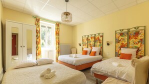 Quarto de hotel com duas camas, um guarda-roupa, um radiador e uma janela com cortinas.