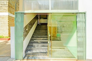 A staircase leading to a building entrance with a glass door and a brick wall. - Classic With Twin Bed Kaveri Road Mysore (Mysore)