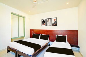 A hotel room with two beds, a wooden headboard, a large mirror, and three wall art pieces. - Classic With Twin Bed Kaveri Road Mysore (Mysore)