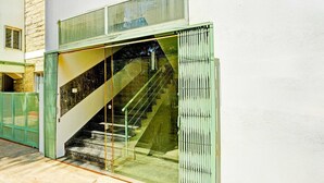 A modern building with a glass entrance, a visible staircase, and a green door. - Classic With Twin Bed Kaveri Road Mysore (Mysore)