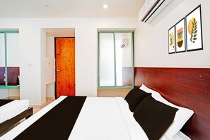 A hotel room with a bed, a wooden door, a window, and a wall-mounted air conditioner. - Classic With Twin Bed Kaveri Road Mysore (Mysore)