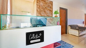 A reception area with a marble wall, a glass railing, and a sign indicating it's company-serviced. - Classic With Twin Bed Kaveri Road Mysore (Mysore)