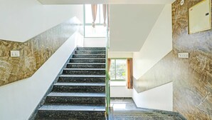 A staircase with marble walls and a glass railing, leading to a room with a window and curtains. - Classic With Twin Bed Kaveri Road Mysore (Mysore)