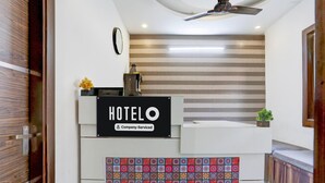 Ein Hotelrezeptionstresen mit einem Schild, auf dem 'HOTEL O' steht, und einem Etikett mit Firmenlogo.