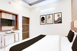 A hotel room with a bed, a TV, a small table with cups and a kettle, and three framed artworks on the wall. - Saver Double Hotel Prabhat (Dera Bassi)