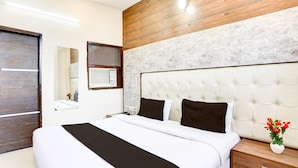 Ein modernes Hotelzimmer mit einem großen Bett, einer Wand mit Holzverkleidung, einem Marmorkopfbrett und einem Nachttisch mit Blumen.