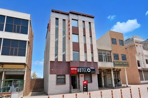 A hotel with a modern facade, a visible reception area, and a sign indicating the availability of a mobile booking app. - Saver Double Hotel Prabhat (Dera Bassi)