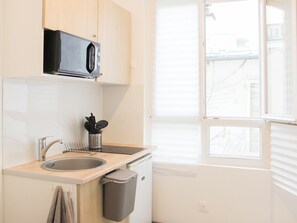 A kitchen with a microwave, sink, and trash bin. - Studio near Roland Garros and Parc des Princes (Boulogne-Billancourt)