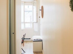 A room with a large window, a white bench, and a door leading to another room. - Studio near Roland Garros and Parc des Princes (Boulogne-Billancourt)