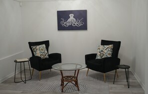 Ein Zimmer mit zwei schwarzen Sesseln, einem Glastisch und einem Teppich mit Muster.