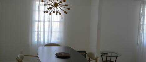 A dining area with a table, chairs, a chandelier, and a small round table.