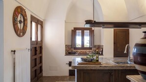 Una cocina con una isla de madera, un reloj grande y una ventana con vistas.