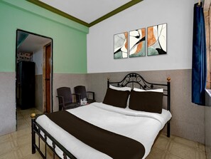 Ein Hotelzimmer mit einem Bett, zwei Stühlen, einem Gemälde und einem fenster mit Vorhängen.