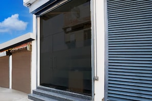A building with a closed shutter door, a set of steps leading to a door, and a clear sky in the background.