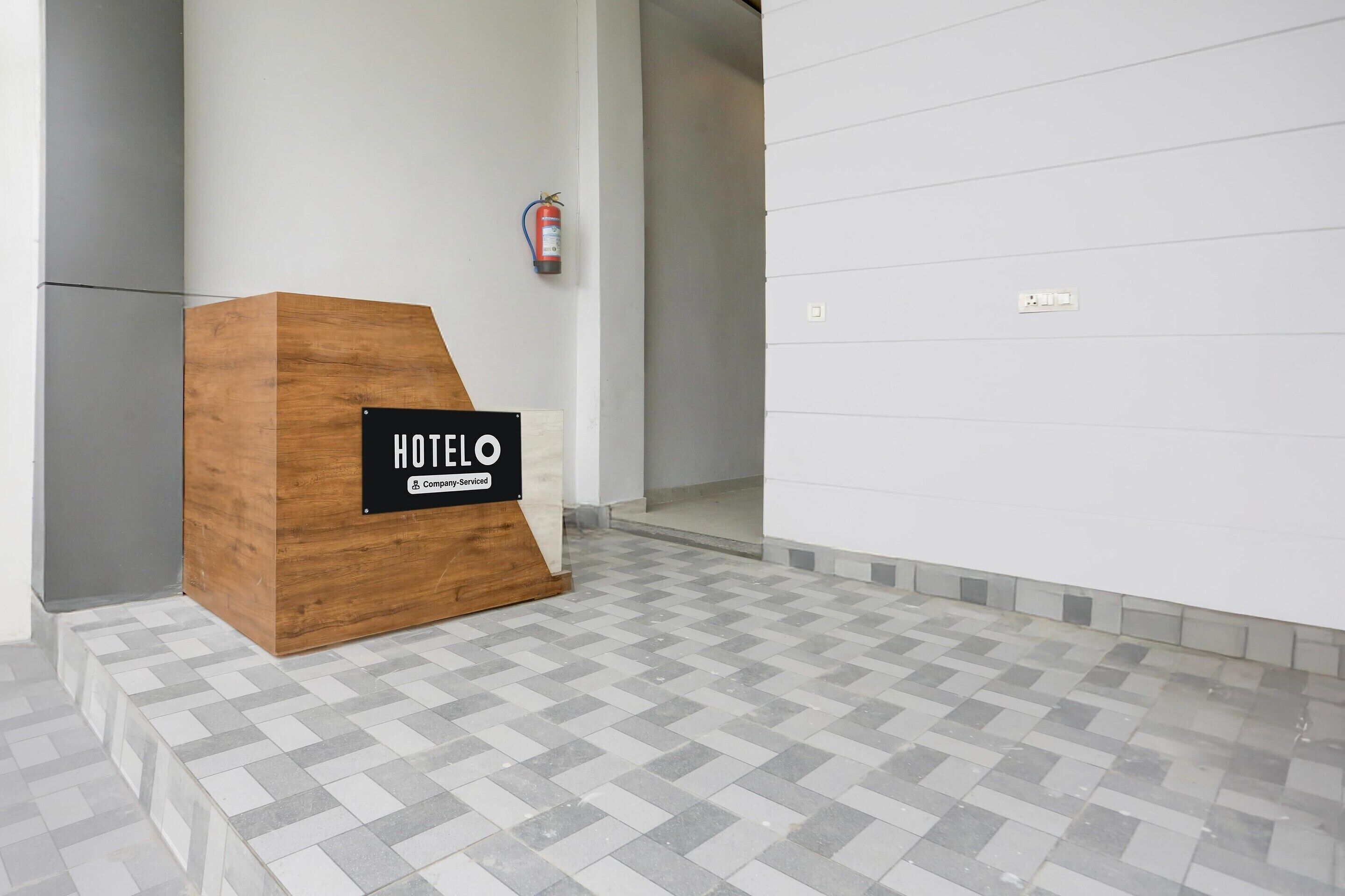 Un mostrador de recepción de hotel con un cartel que dice 'HOTEL O' y un extintor de incendios en la pared.