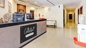 A hotel reception area with a reception desk, a water dispenser, a bed, and a hallway. - Super Deluxe Room Jagadamba Junction (Visakhapatnam)