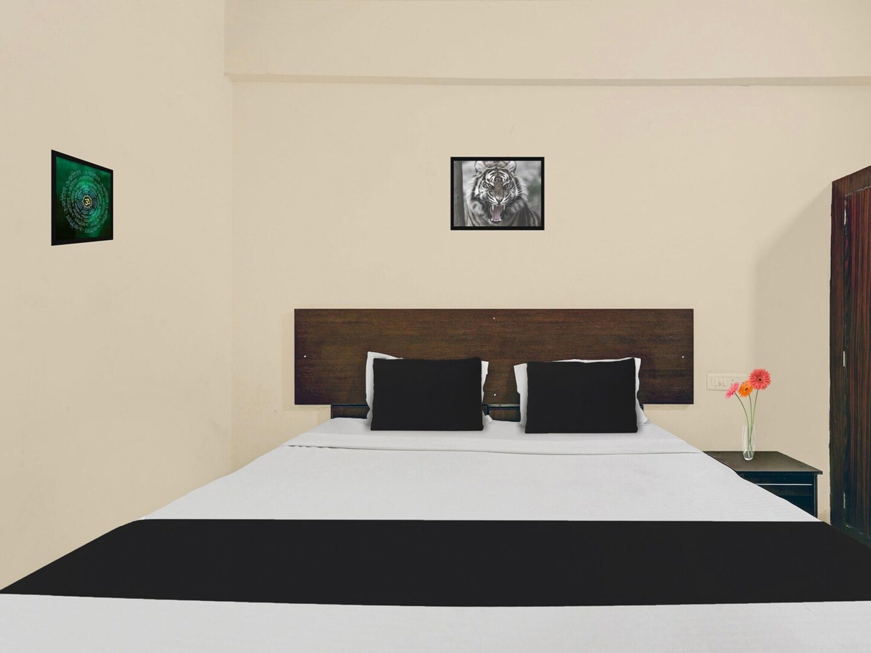A bed with a dark headboard, two black pillows, and a white bedspread.