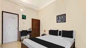 A hotel room with a bed, a desk, a chair, a wardrobe, and a picture on the wall. - Super Deluxe Room Jagadamba Junction (Visakhapatnam)