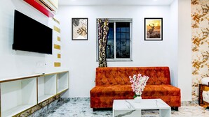 A living room with a sofa, a flat-screen TV, a window with curtains, and artwork on the walls. - Saver Double Circus Avenue Rockstar (Kolkata)
