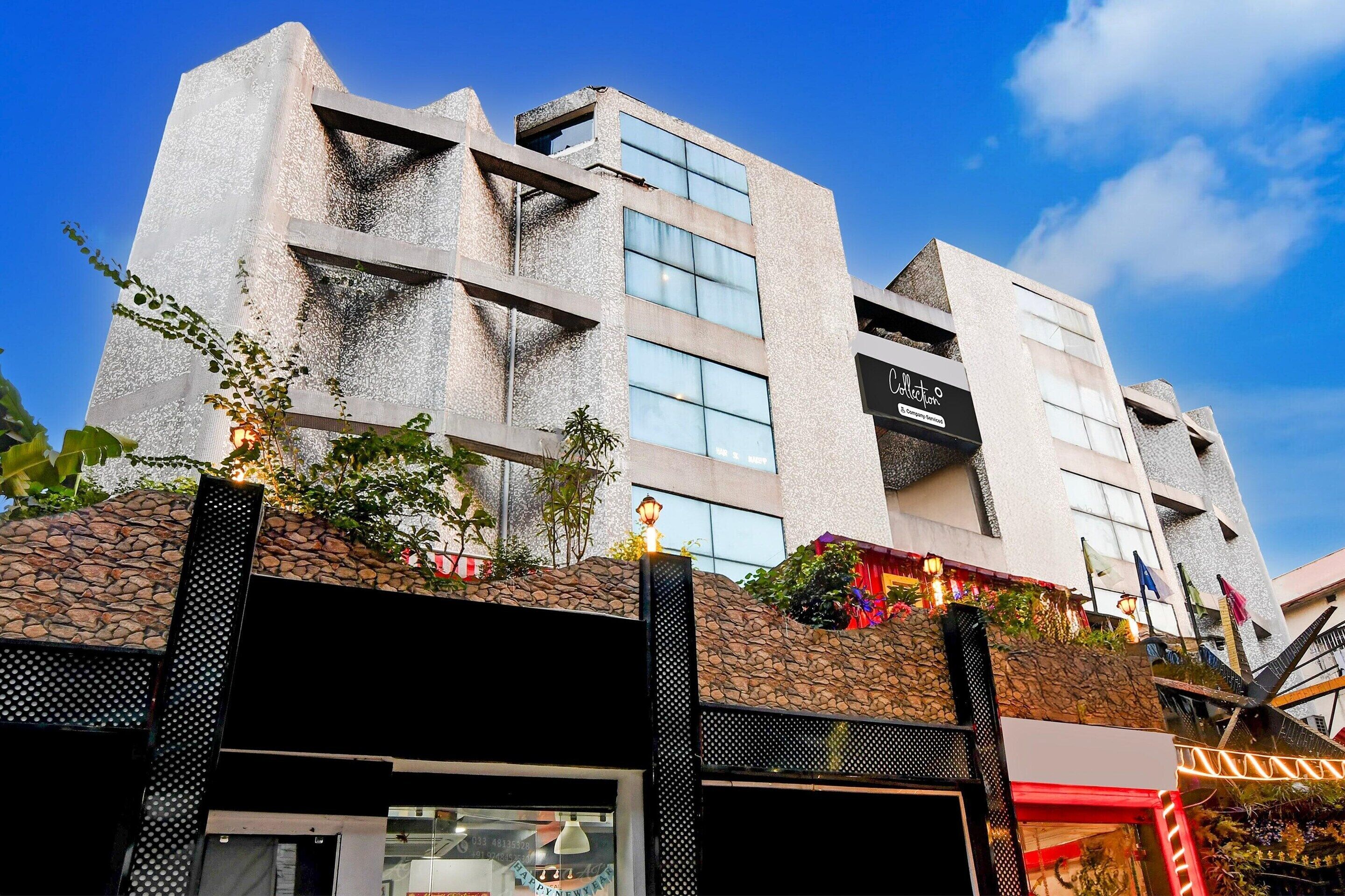 A modern building with a stone facade, large windows, and a sign that reads 'Collection.'