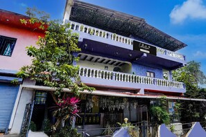 A multi-story building with a balcony, a sign reading 'Collection,' and lush greenery around. - Classic With Balcony Traveller Guest (Calangute)
