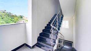 Un interno moderno con una scala nera, pareti bianche e vista sul verde.