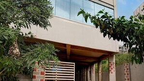 A modern building with a covered entrance, a tiled pathway, and a brick wall. - Deluxe Smart Stays (Vijayawada)
