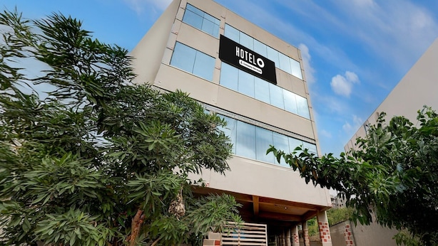 A modern hotel with a 'HOTELO' sign, a covered entrance, and a brick wall. - Deluxe Smart Stays (Vijayawada)