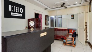 A hotel reception area with a reception desk, a globe, a clock, and a sofa. - Deluxe Smart Stays (Vijayawada)