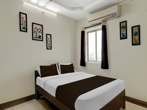 A bedroom with a bed, a window with curtains, and wall-mounted air conditioning.