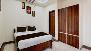 A bedroom with a bed, a wardrobe, and wall art. - Deluxe Smart Stays (Vijayawada)