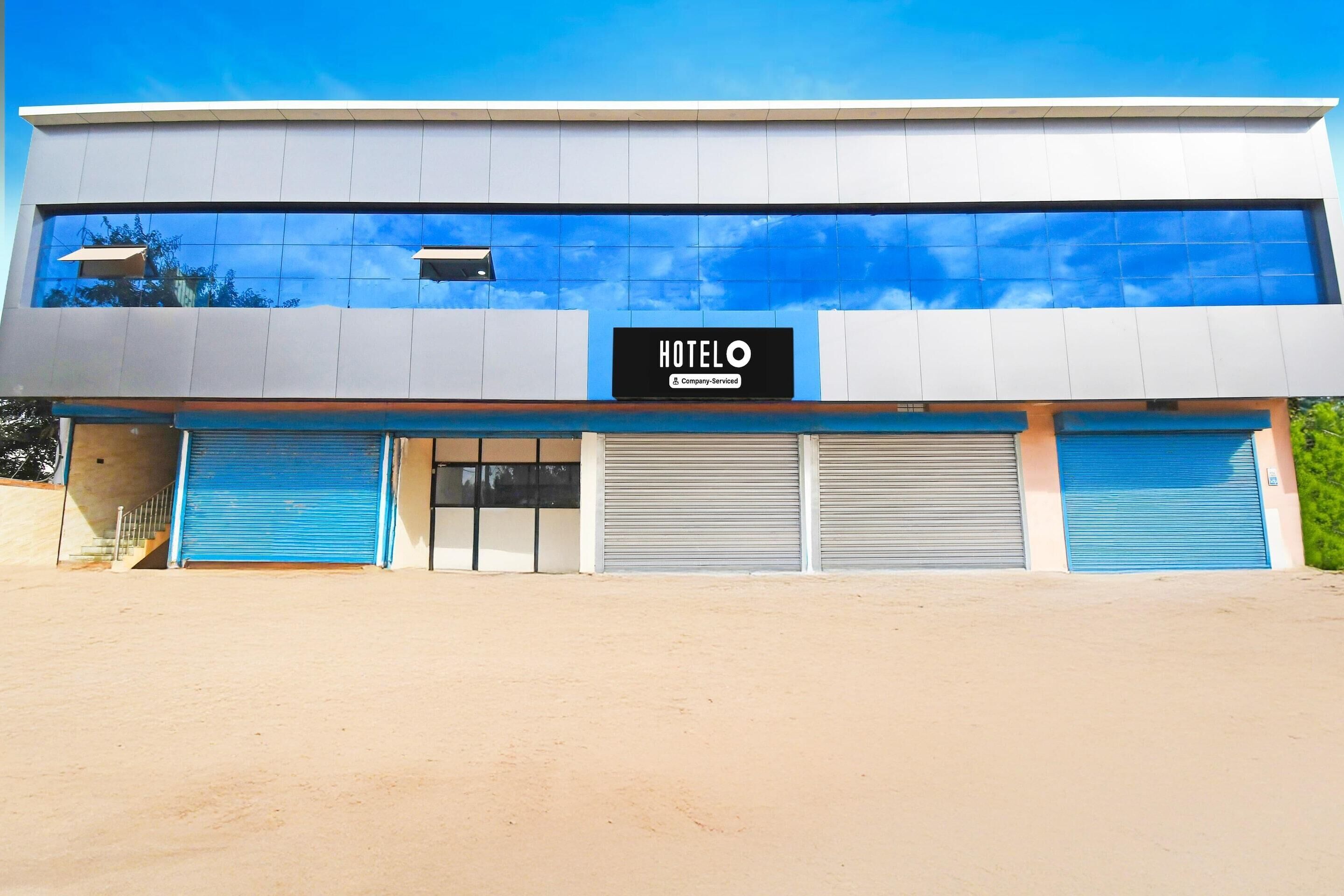 A modern hotel building with a sign reading 'HOTELO & Company-Serviced,' large windows, and closed shutters.