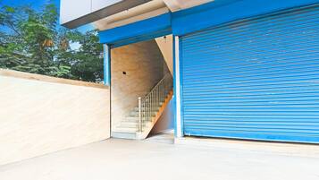 A building entrance with a blue shutter, a staircase leading inside, and a beige wall.