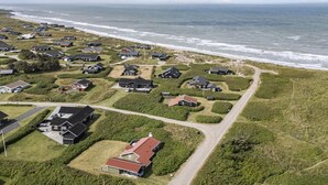 Vue aérienne d’une zone résidentielle côtière, avec des maisons, des routes et une plage.