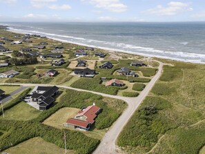 Vista aérea de una zona residencial costera con casas, carreteras y una playa.
