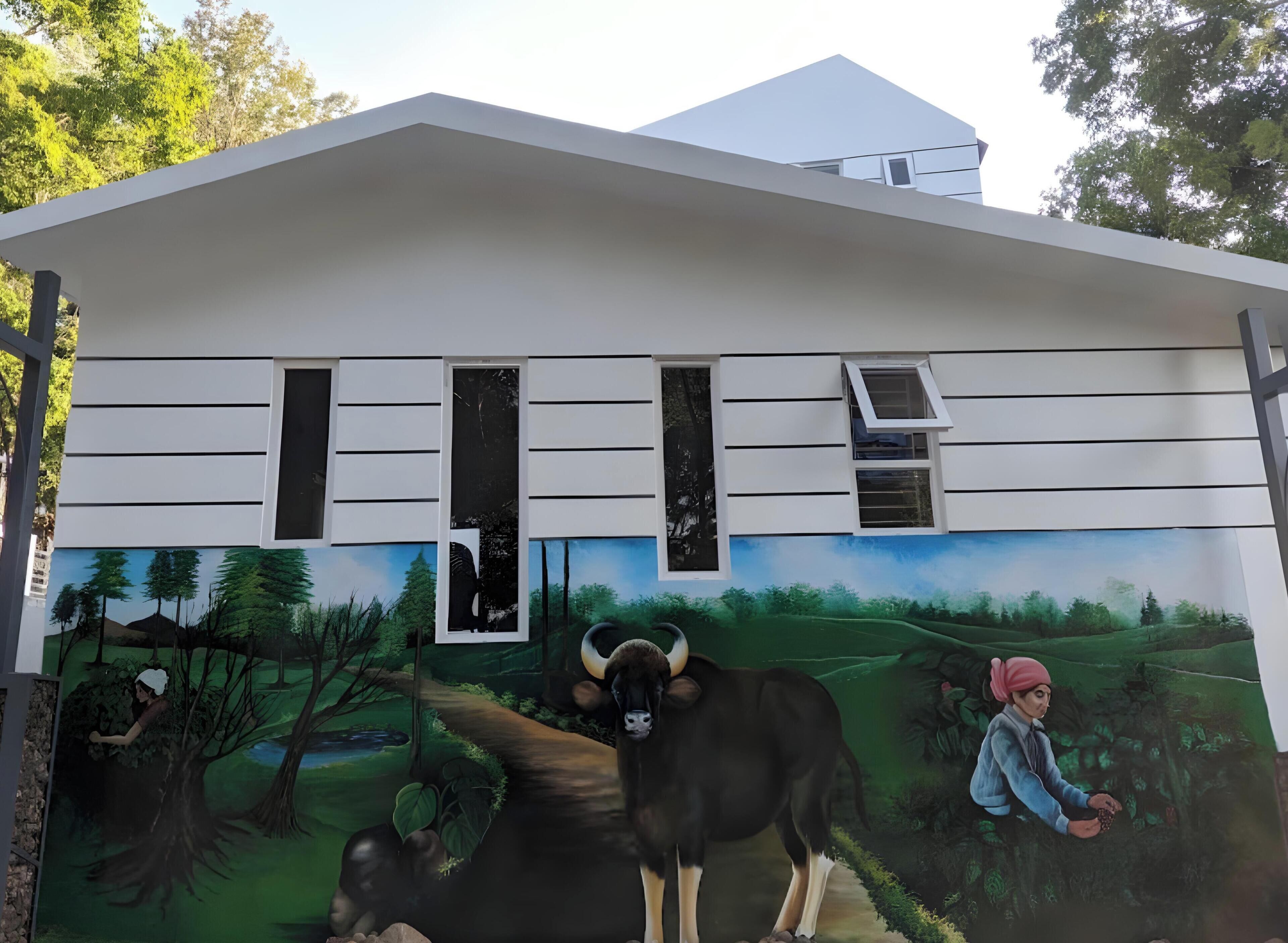 A building with a mural of a landscape, a cow, and a person.