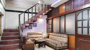 A staircase with a handrail, a sofa, a coffee table, and a window with blinds. - Deluxeharry Guest House (Bidhannagar)