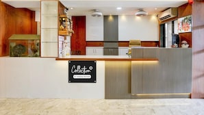 A modern reception area with a marble floor, wooden accents, a 'Collection' sign, and a glass display case.