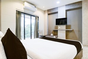 A hotel room with a bed, a TV mounted on the wall, a window with curtains, and an air conditioning unit. - Deluxe Ghodbunder Rd Sanwith Residency (Mumbai)