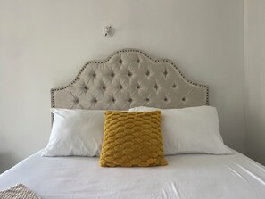 A bed with a tufted headboard, white pillows, and a mustard-colored throw blanket. - Bright Bay Garden Suite/Wi-fi/ 15 mins beach/ 20 min airport (Montego Bay)