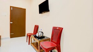A room with a wooden door, a television mounted on the wall, and a table with chairs.