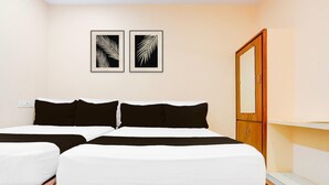 A double bed with white and black bedding, a wooden headboard, a wooden wardrobe, and two framed leaf artworks on the wall.