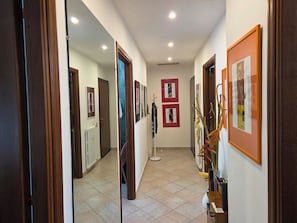 A hallway with framed artwork on the walls, a radiator, and a plant. - Sapore di Langhe: Holiday House in the Center with Garage (Alba)
