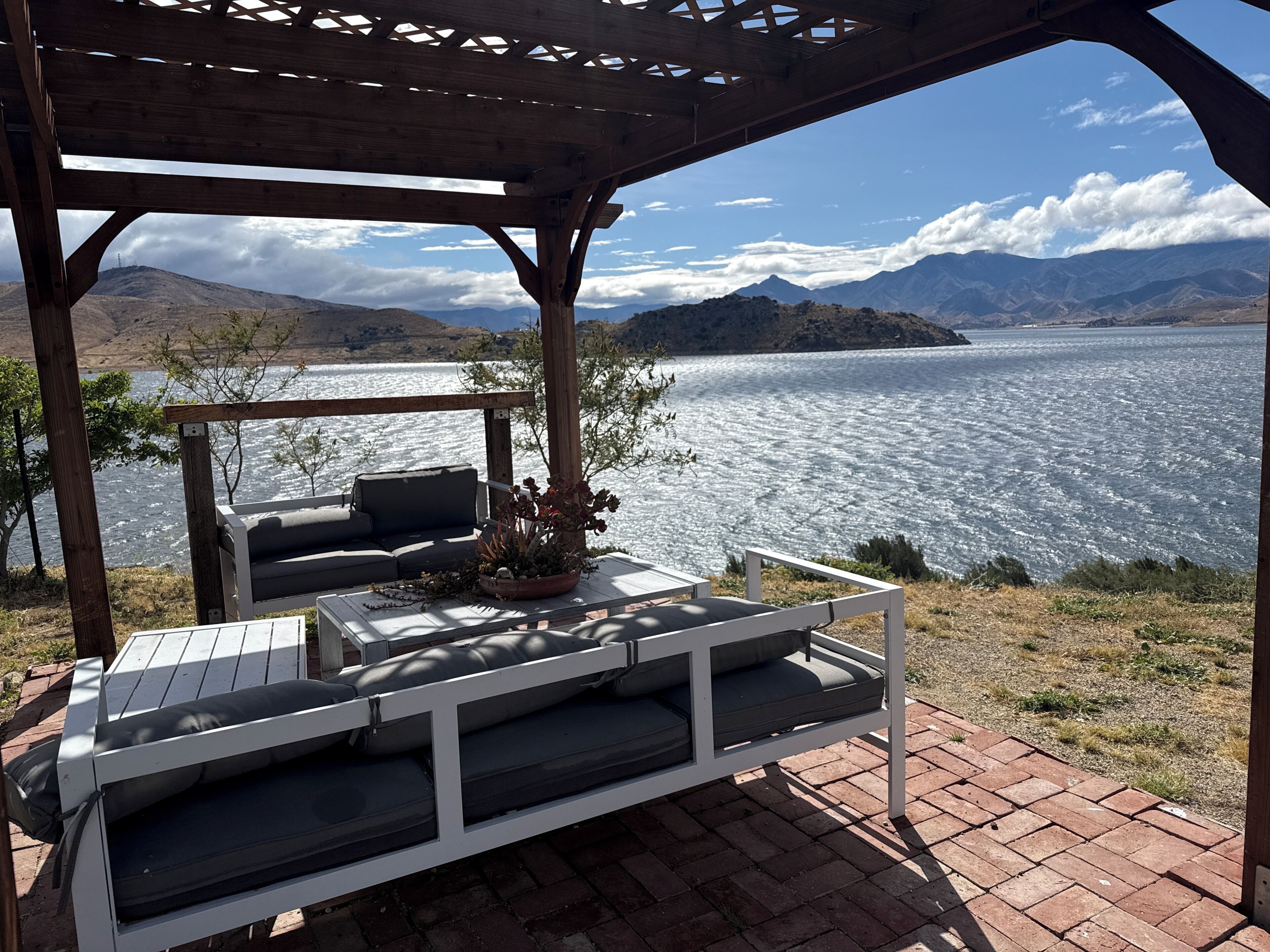 A covered outdoor seating area with a view of a lake and mountains.