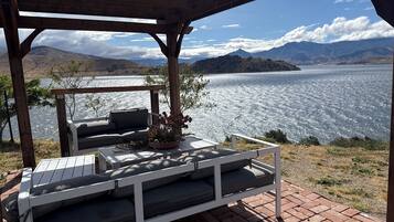 A covered outdoor seating area with a view of a lake and mountains.