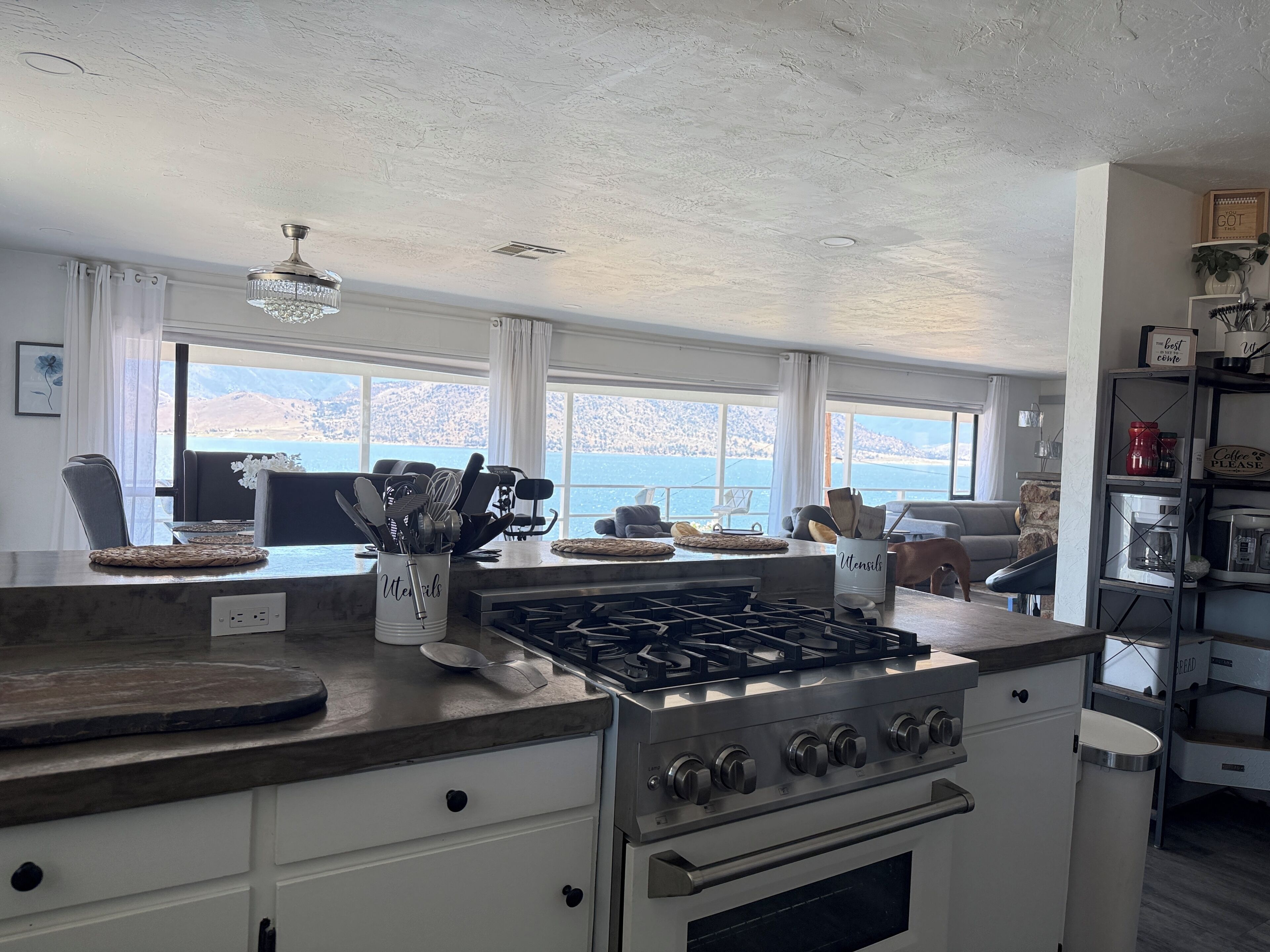 Una cocina con estufa a gas, cafetera y vistas al mar.