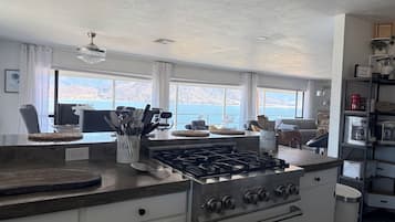 Una cocina con estufa a gas, cafetera y vistas al mar.