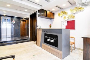 Una reception con una insegna che recita 'TOWNHOUSE Company Serviced', una porta in legno, un ascensore in vetro e un ventilatore a parete.